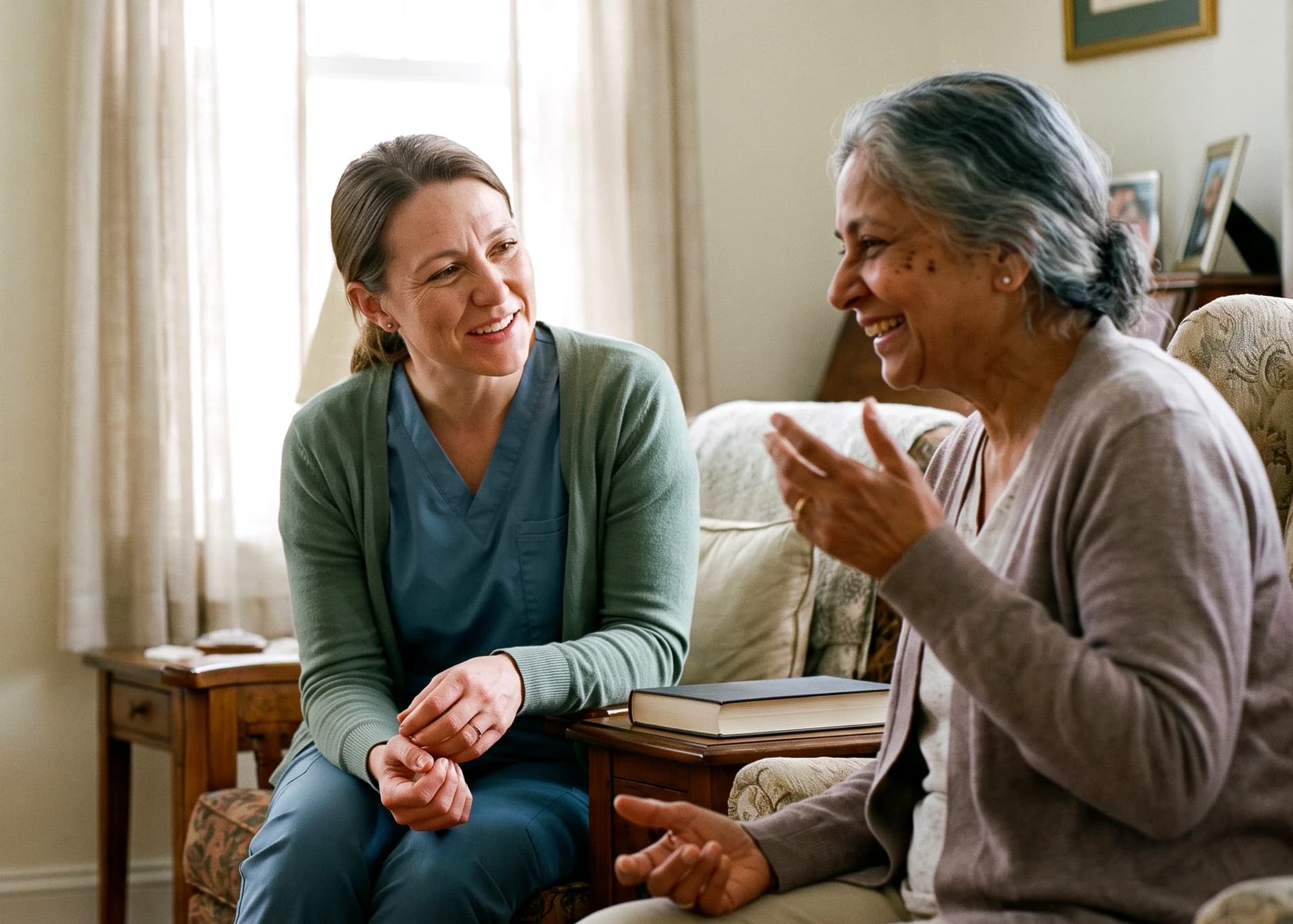A caregiver sitting with an older woman in her living room, mid-conversation