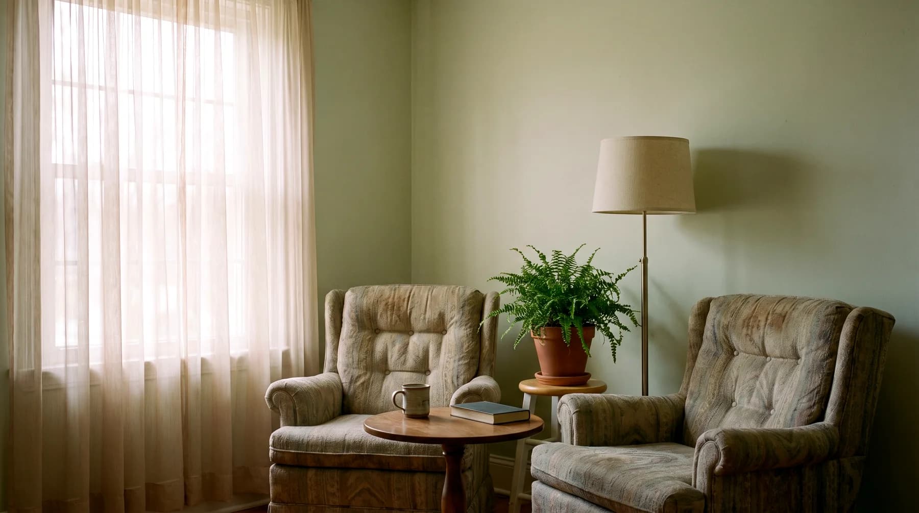 Two empty armchairs in a living room with morning light through sheer curtains